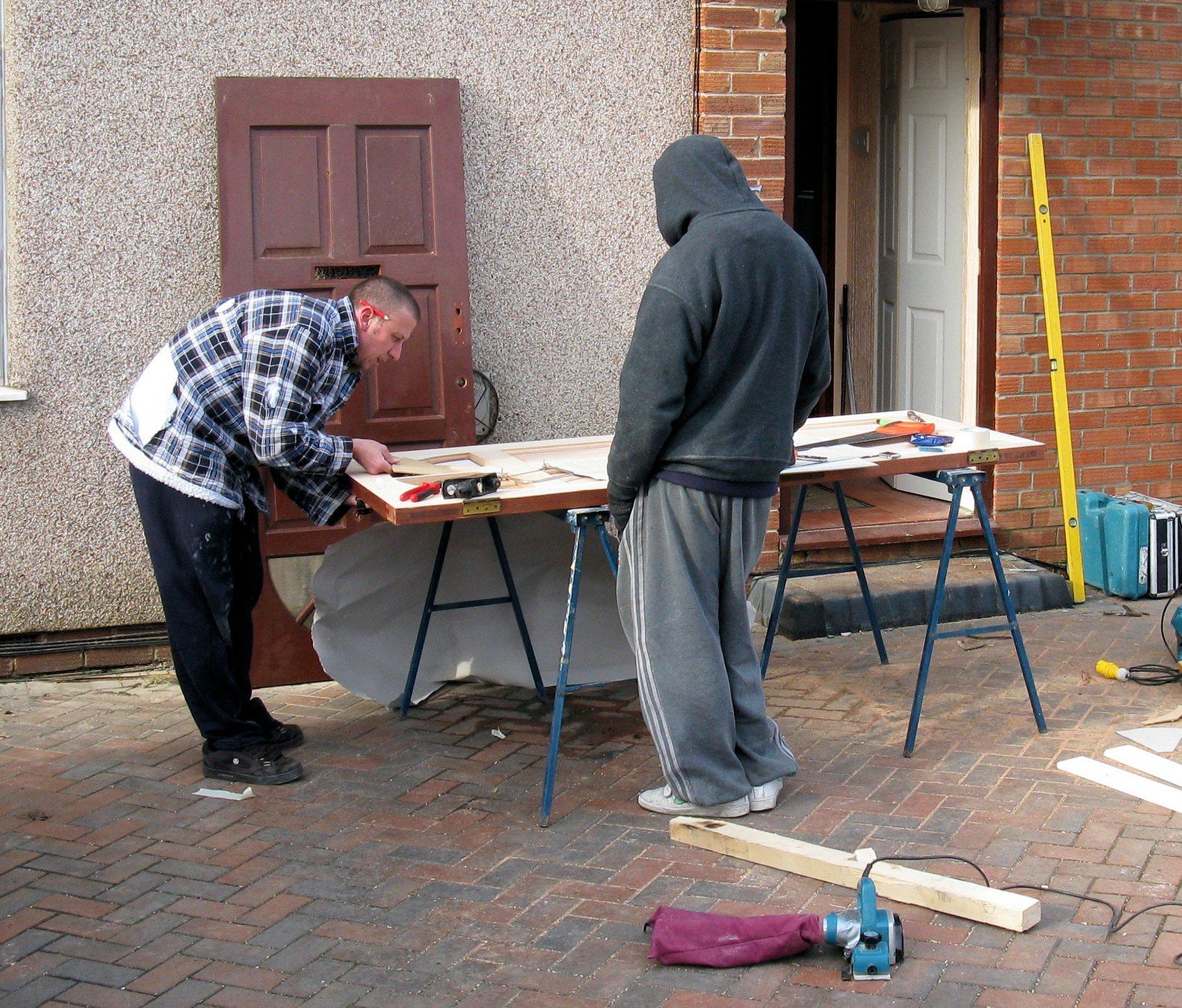 Tradespeople repairing and fitting a door at a property