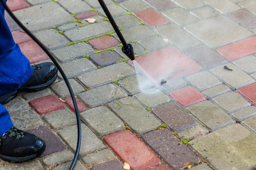 Pressure washing built-up grime from a paved driveway